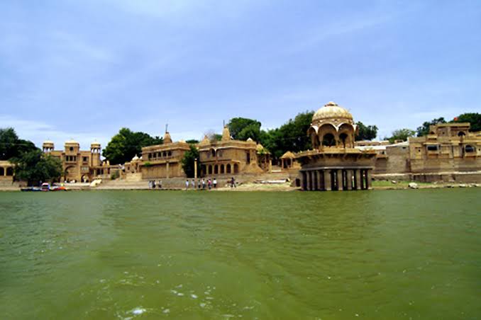 Tourists enjoying a peaceful boat ride at Gadisar Lake, Jaisalmer.